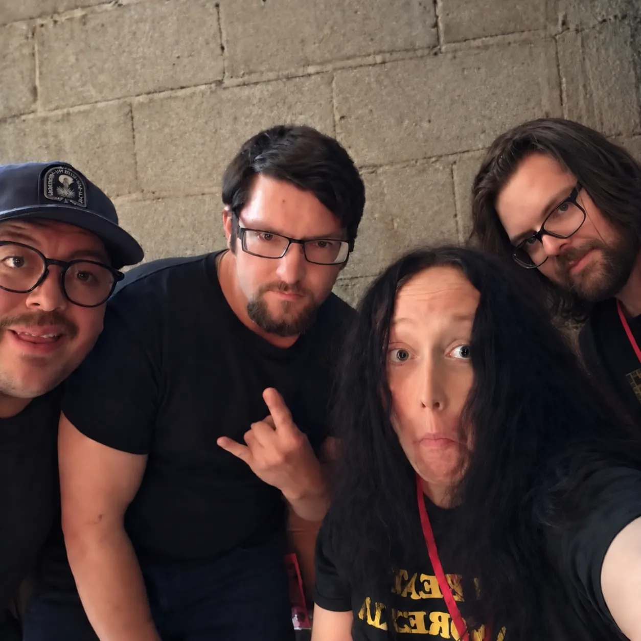 Cir. Ëlke posing together for a group selfie against a concrete wall